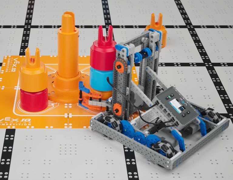 The hero robot on the VIQRC field with a stack of 3 pins in it's claw. The robot is in position to stack the pins on the yellow standoff goal.