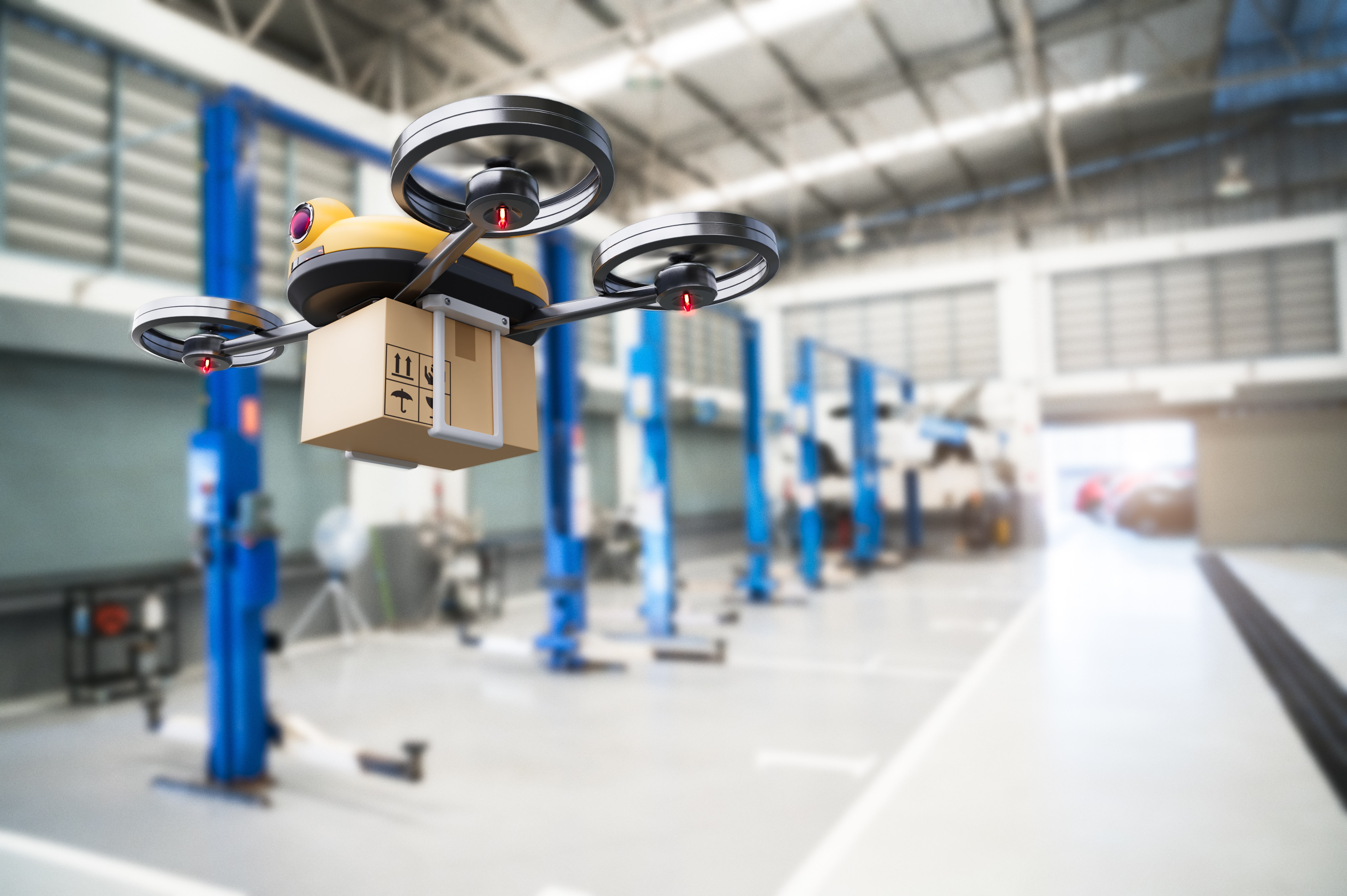 A drone carries a small box through a warehouse.