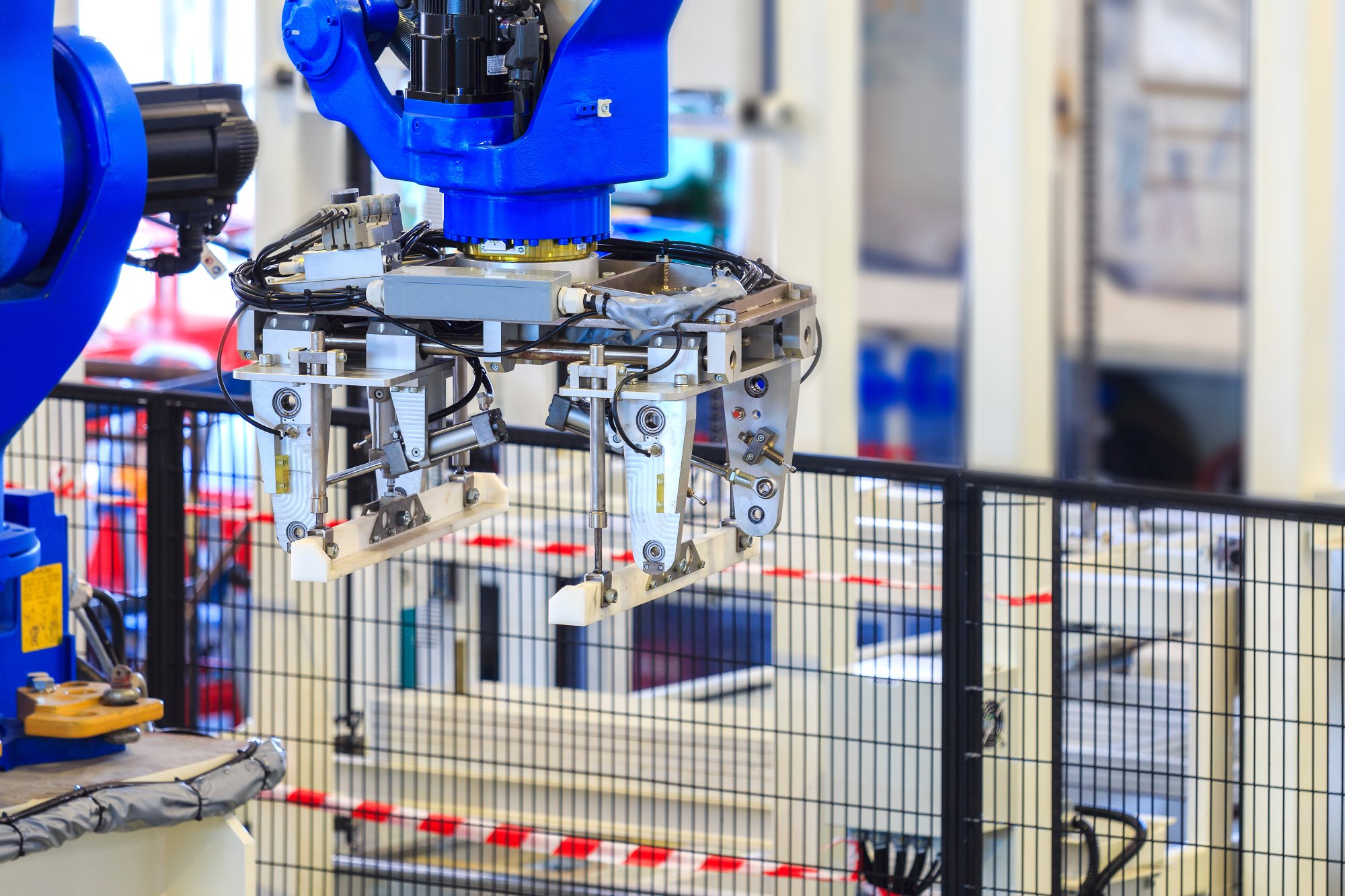 Photo of an industrial robot with an fence surrounding it to protect others from approaching the robot while it is in motion.