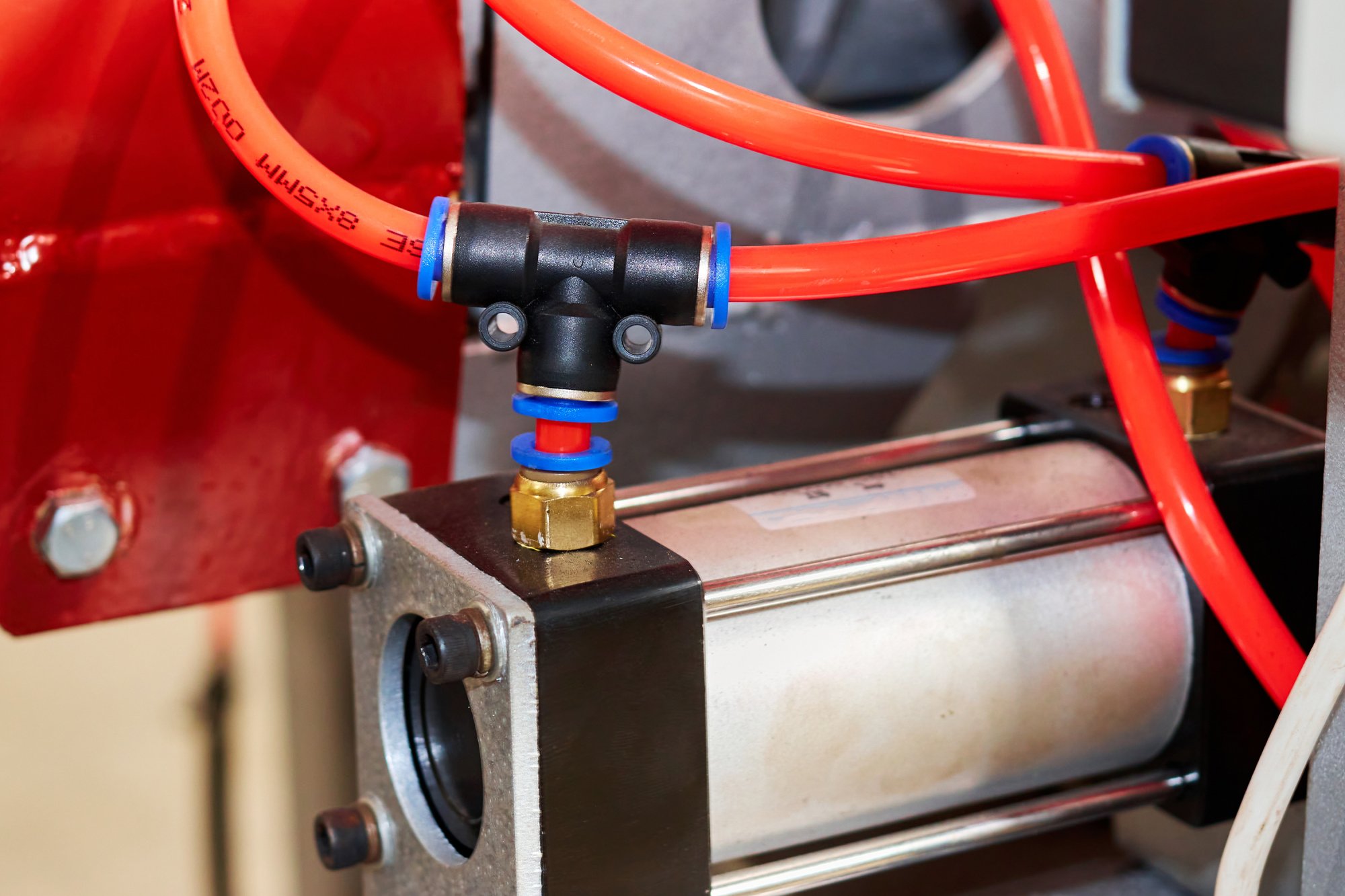 Pneumatic cylinder with tubing attached in a factory setting.