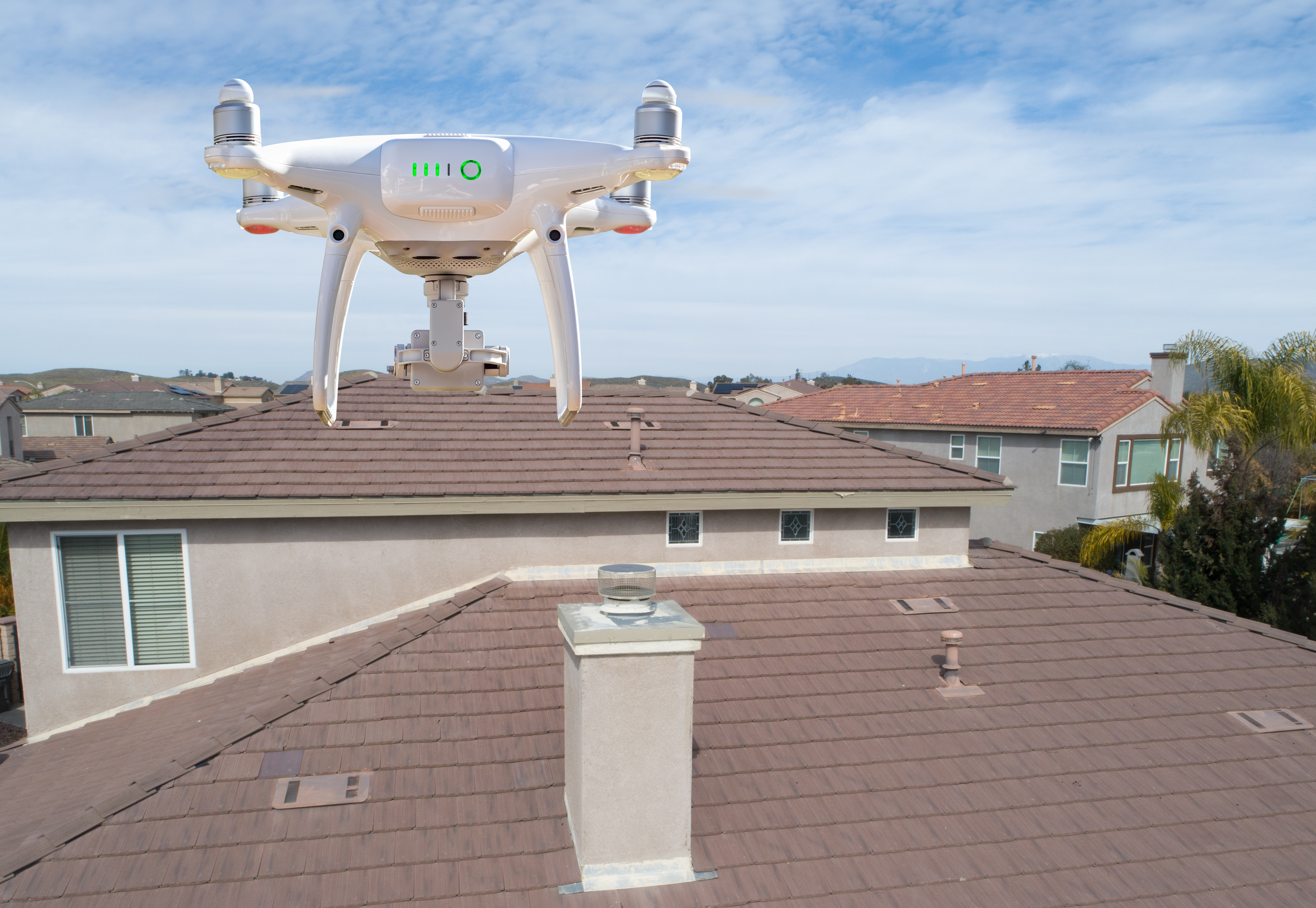A drone flies over a house in a neighborhood to help inspect a roof for damage.