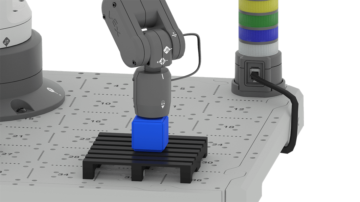 An angled view of the 6-Axis Robotic Arm with the Magnet Pickup Tool. The tip of the tool is touching a blue cube that is on a pallet.
