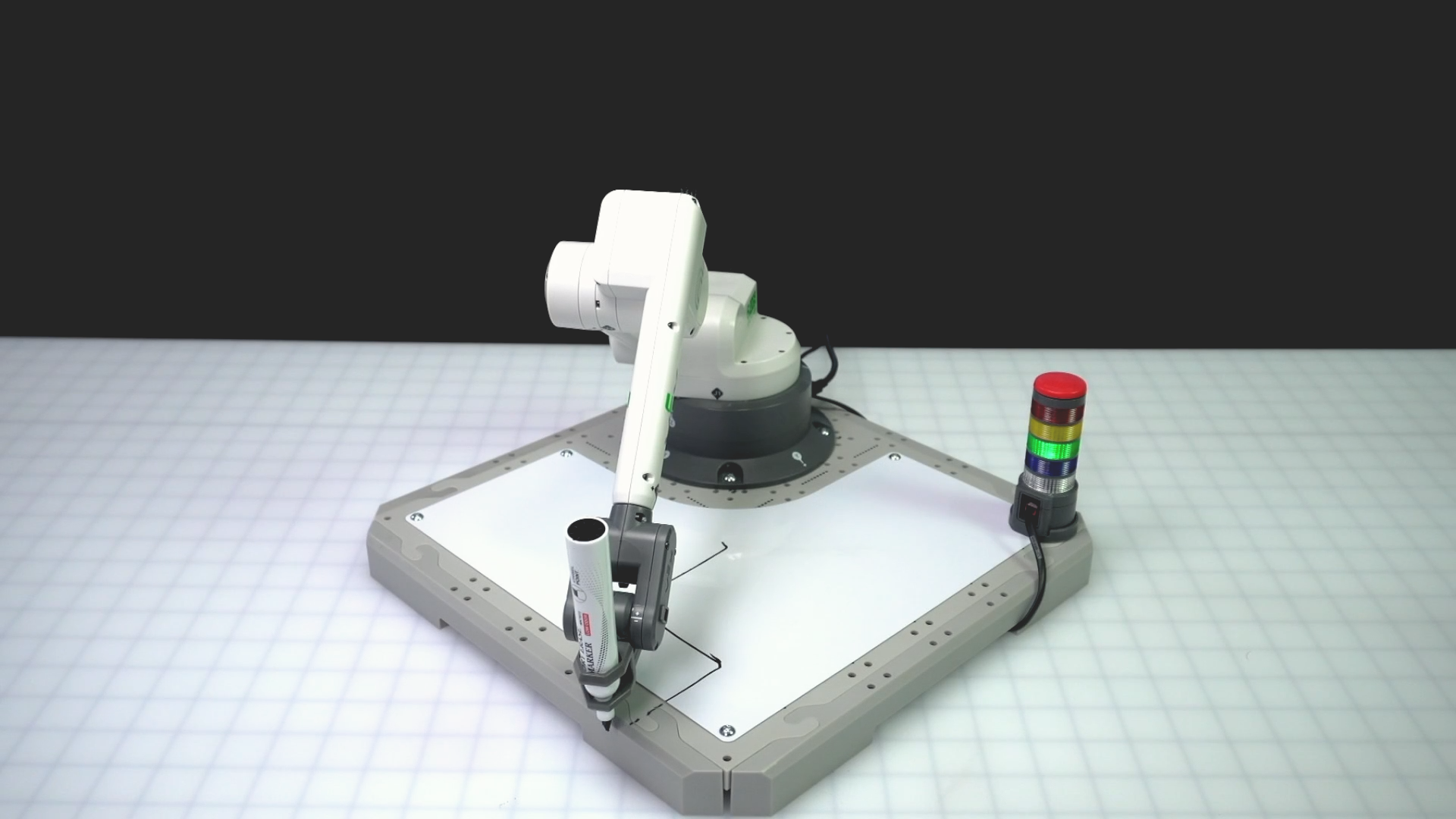 Angled view of the 6-Axis Arm after drawing the first two sides of the square correctly and then moving off the Tile for the next behavior. The black line of the whiteboard shows the path the arm took while drawing.