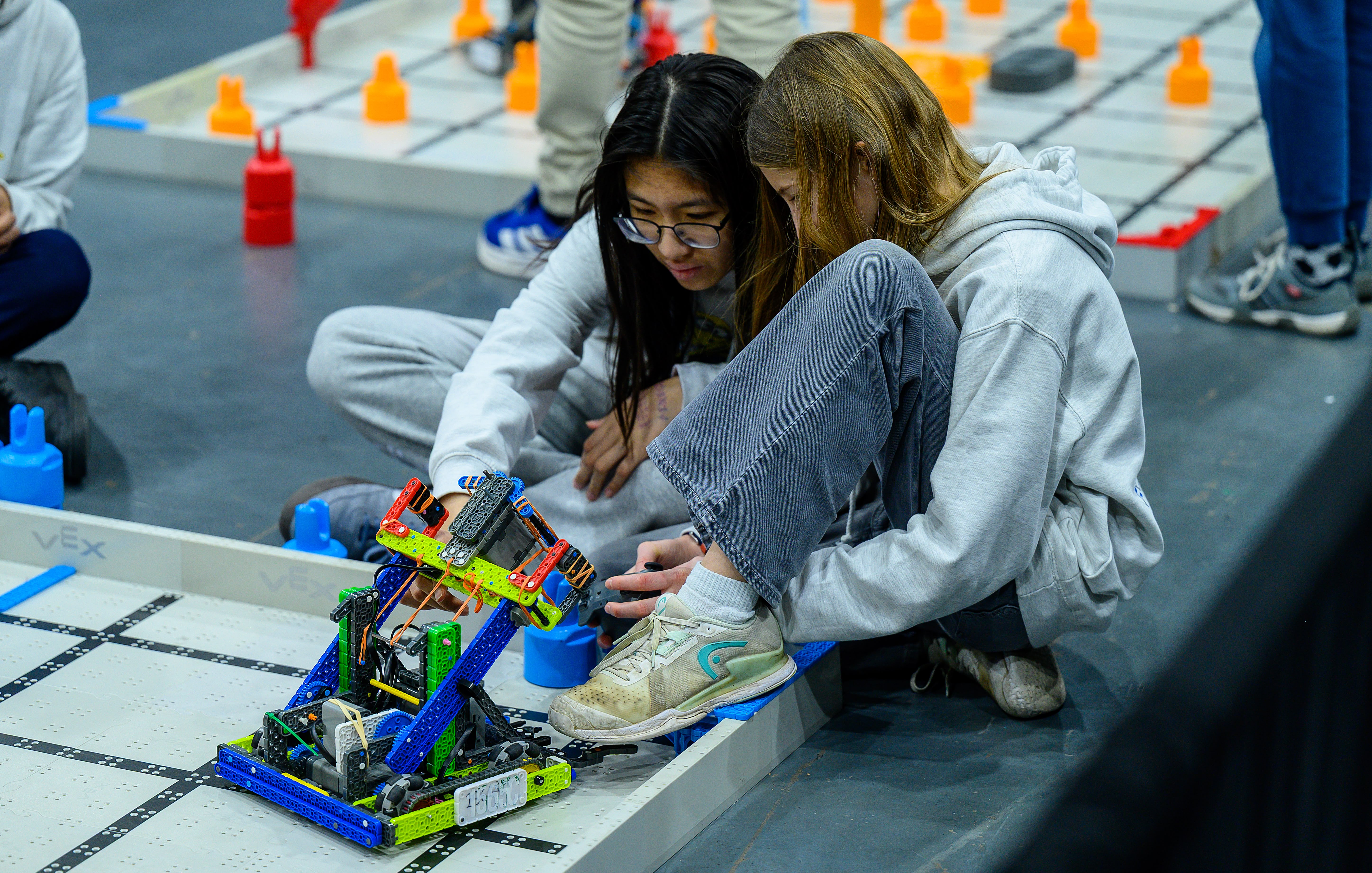 Two VEX IQ Competitors examine their robot on the field.