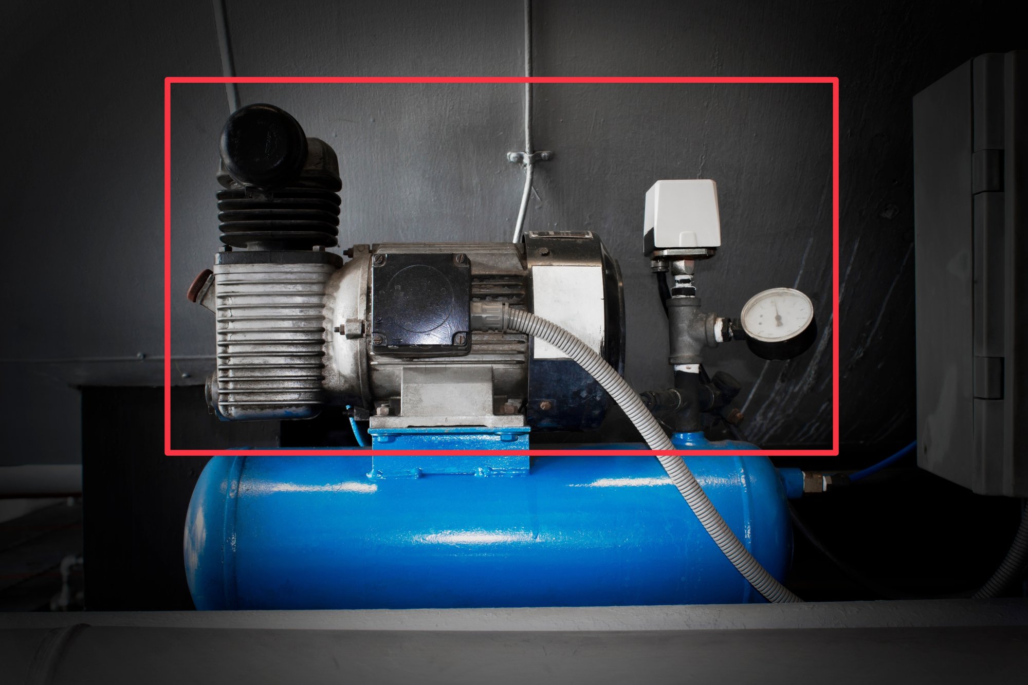 An industrial air compressor sitting on top of an air tank, with the a red box around the compressor.