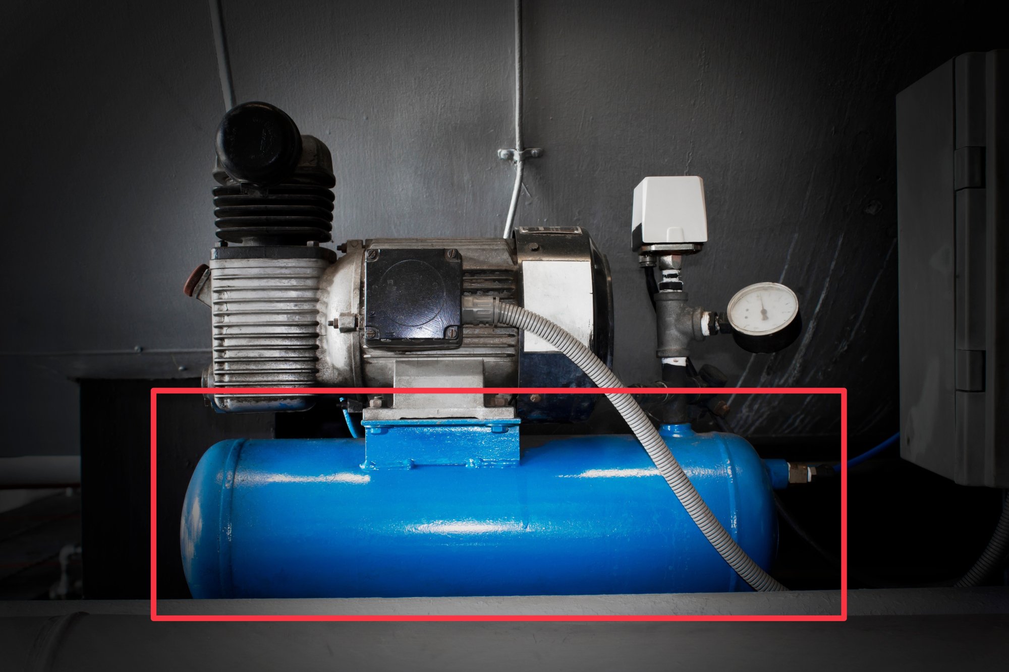 The same image as above, of an industrial air compressor atop an air tank, but with a red callout box around the air tank.