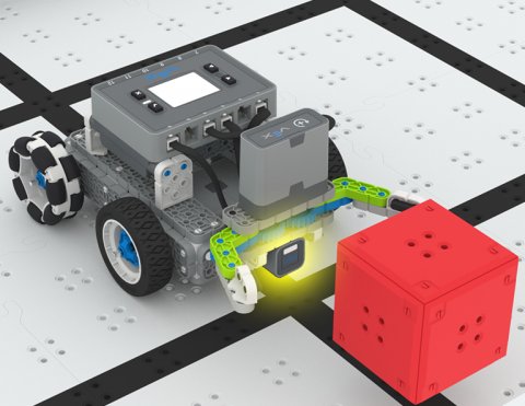 A VEX IQ Simple Clawbot on a Field with the claw open, approaching a red cube. At the base of the claw an Optical Sensor is attached to the robot and is highlighted.